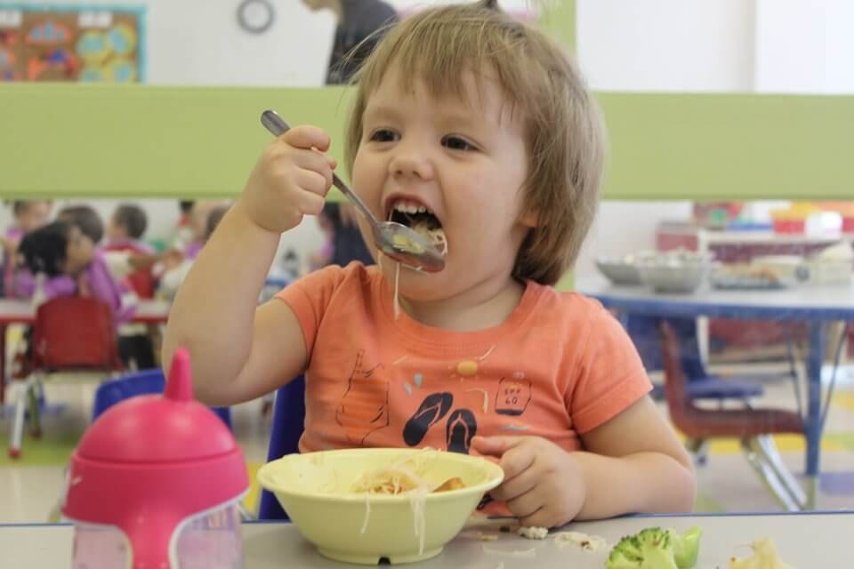 Toddler eating noodles at daycare