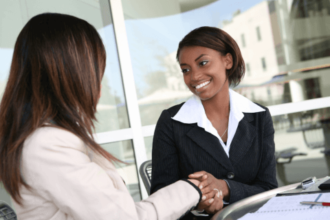 Corporate women shaking hands and smiling